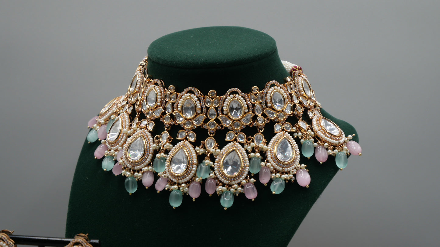 Aurora - A sophisticated Tyaani Kundan set featuring stunning pearl accents and dangling green and pink beads for a captivating display. Includes Jhumka earrings (2.4 inches)