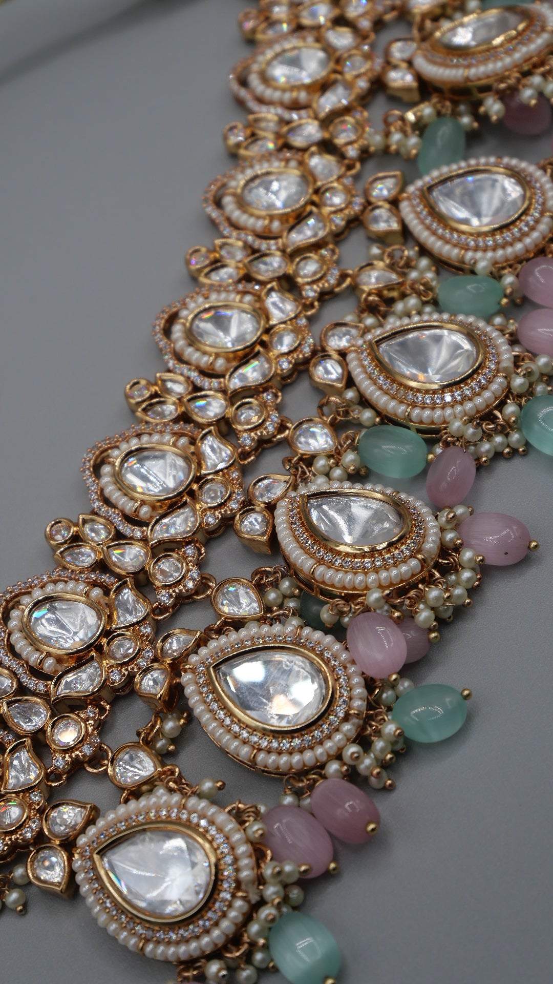 Aurora - A sophisticated Tyaani Kundan set featuring stunning pearl accents and dangling green and pink beads for a captivating display. Includes Jhumka earrings (2.4 inches)